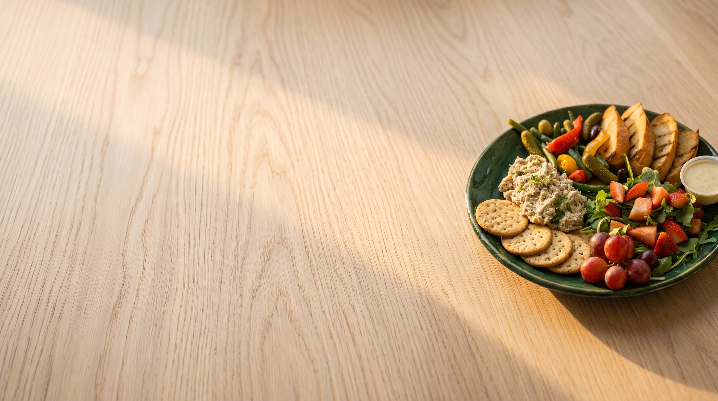 Chicken salad with fresh greens and fruit on a pale oak table